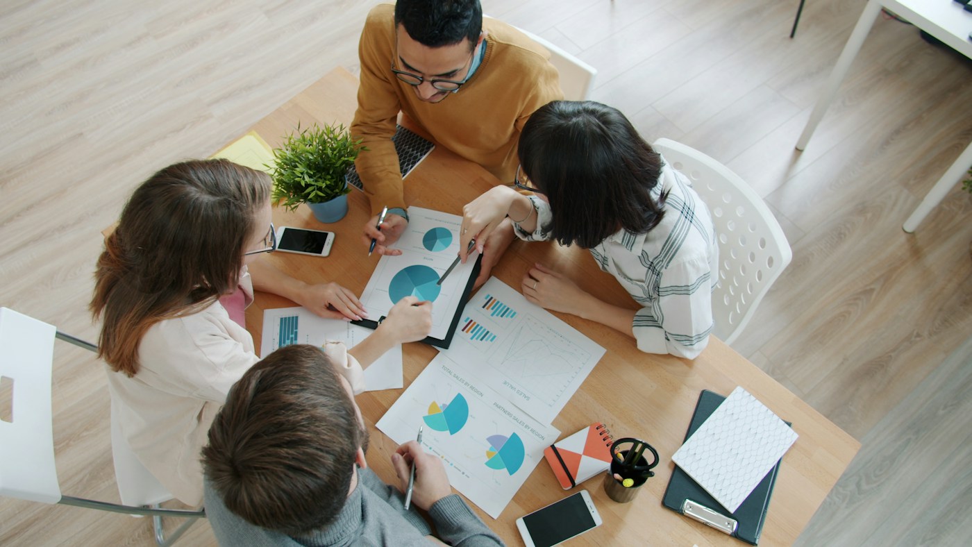 Overhead view of colleagues discussing charts together at a table